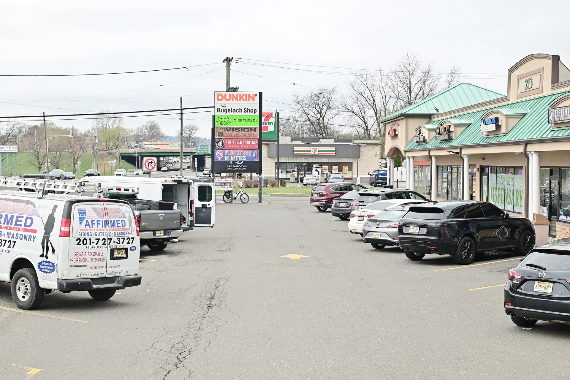 wide parking lot view of Ohm Theory dispensary location in Elmwood Park NJ near Exxon sign and Route 46 serving Lodi and Saddle Brook